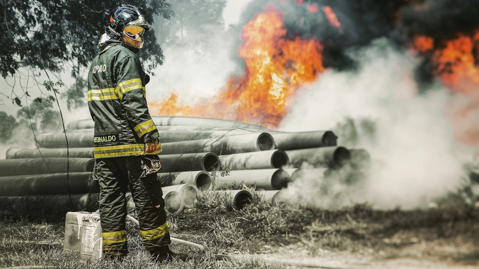 A Fireman in Uniform Standing Near the Blazing Fire